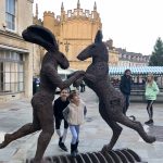 Four people standing next to a statue of two hares in Cirencester town centre 